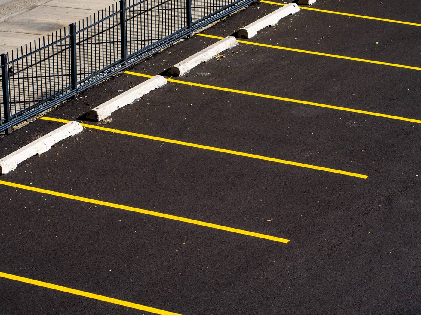 Freshly painted yellow parking stall lines on new black asphalt