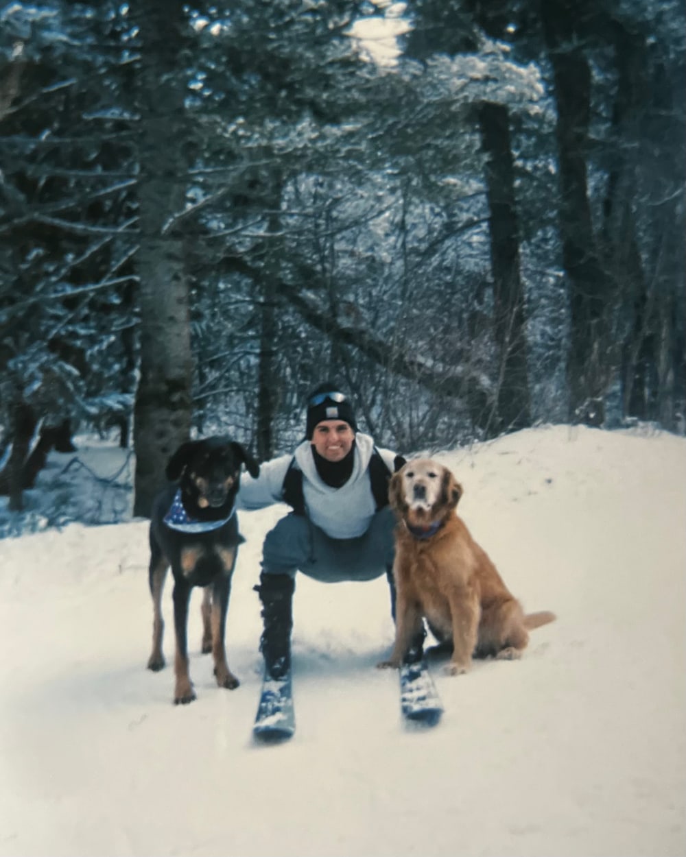 The owner of Mojo Line Striping outdoors in the snow with his two dogs